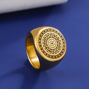 Detailed close-up of golden stainless steel signet ring with engraved mandala patterns