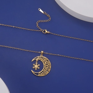 Detailed shot of gold crescent moon and snowflake pendant on a minimalist chain necklace