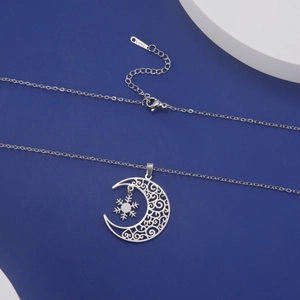 Detailed macro view of moon and snowflake pendant on polished stainless steel chain