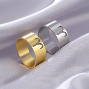 Detailed close-up of gold and silver Aries zodiac rings on purple silk fabric