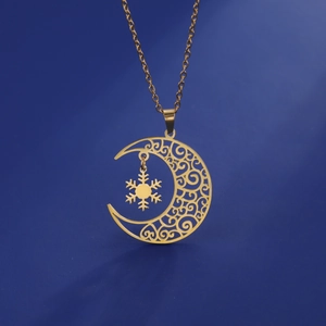 Detailed view of golden moon and snowflake pendant with intricate filigree texture