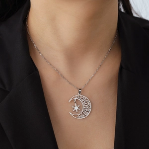 Close-up of a silver crescent moon and snowflake pendant worn on a female model