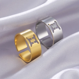 Close-up of gold and silver H-shaped hollow rings on soft purple silk fabric