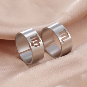 Detailed view of silver Virgo zodiac sign cutout rings on champagne silk fabric