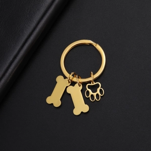 Détail d'un porte-clés en acier inoxydable doré avec pendentifs os et pattes sur cuir