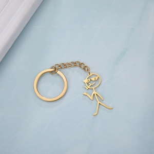 Detailed view of a gold-colored stickman pendant with pixel sunglasses and a key ring