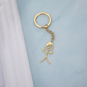 Detailopname van grappige gouden poppetje-sleutelhanger die een middelvinger opsteekt