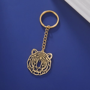 Golden origami tiger head keychain made of stainless steel on dark blue background
