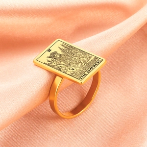 Macro detail of golden The Empress Tarot ring on a luxury soft silk fabric background