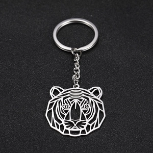 Detailed view of silver geometric tiger head keychain on black textured surface