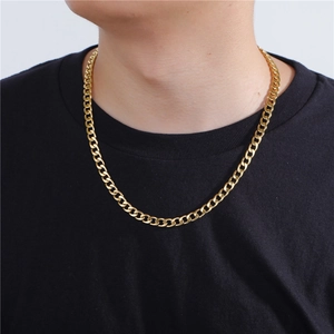 Close-up of a classic gold-toned Cuban curb chain necklace on a model wearing a black shirt
