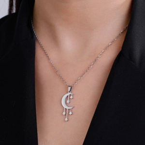 Primer plano detallado del collar de luna creciente y estrellas sobre un blazer negro chic