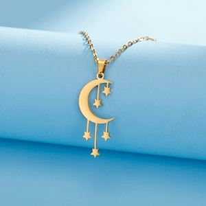 Detalle del collar con colgante de luna creciente y estrellas doradas en soporte azul