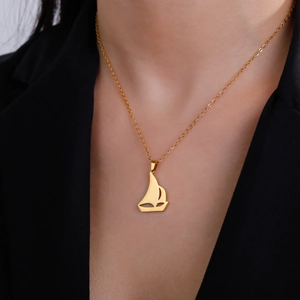 Collar con colgante de velero vikingo dorado en modelo con una chaqueta negra formal
