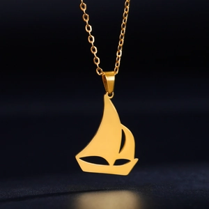Detalle del colgante de velero dorado pulido con una fina cadena de eslabones tipo O