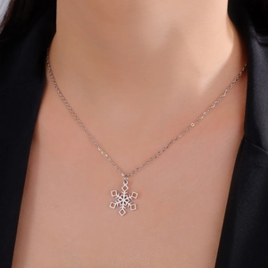 Silver snowflake pendant necklace worn on neck over a black suit, showing fine chain details