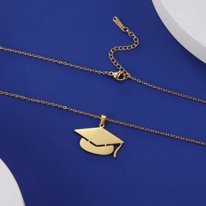 Polished gold doctoral cap pendant necklace on blue background with geometric props