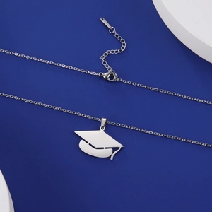 Close-up of silver stainless steel necklace with a graduation cap pendant on a blue stand