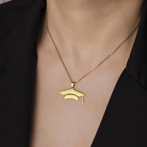 Golden graduation mortarboard cap pendant necklace worn by a model in a black suit