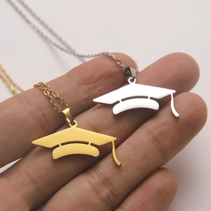 Close-up of gold and silver academic graduation cap pendants on delicate link chains