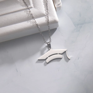Macro detail of silver graduation cap pendant with tassel on stainless steel chain