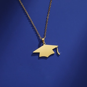 Detailopname van gouden afstudeerhoed hanger met kwastje aan fijne ketting