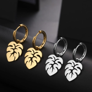 Goldene und silberne Edelstahl-Ohrringe mit Monstera-Blatt-Anhaenger auf Display