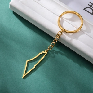 Detail of a gold stainless steel keychain with a hollow geographic map pendant on green back