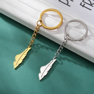 Detail view of gold and silver feather-shaped keychains with a polished metallic finish