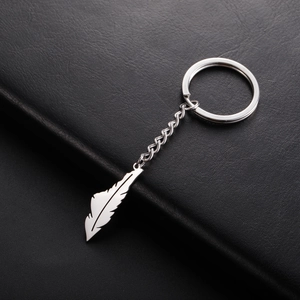 Detailed close-up of a silver stainless steel feather pendant on a dark leather surface