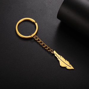 Detailed close-up of a polished gold feather pendant keychain on a dark background
