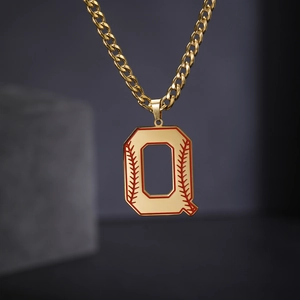 Détail de la chaîne cubaine dorée avec pendentif lettre Q et couture rouge de baseball