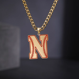Détail de la chaîne cubaine dorée avec pendentif lettre N baseball et coutures rouges