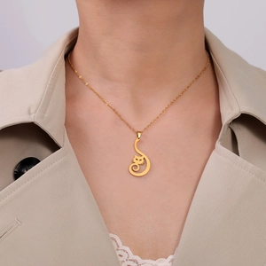 Dettaglio di una collana con ciondolo a forma di gattino dorato indossata da una modella
