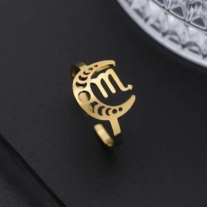 Détail de la bague zodiaque dorée avec croissant de lune sur fond de cuir noir texturé