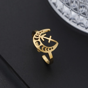 Détail d'une bague Sagittaire dorée avec motif lune évidée sur fond de cuir noir texturé