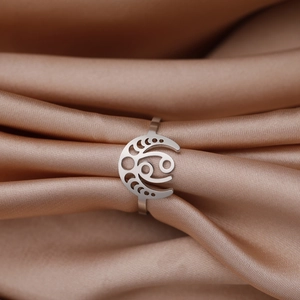 Détail d'une bague zodiaque en acier inoxydable avec signe Cancer sur fond de soie