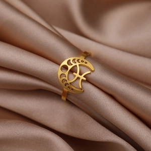 Vue détaillée d'une bague croissant de lune dorée avec symboles célestes sur soie champagne