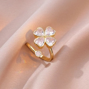 Vista macro de anillo de trébol con circonitas de corazón rosa y acabado dorado en seda