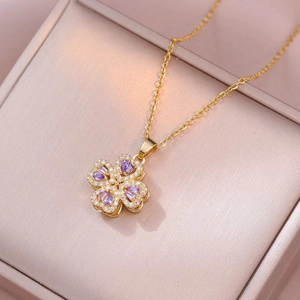 Dettaglio di una collana a quadrifoglio dorata con pietre di zircone viola in scatola regalo