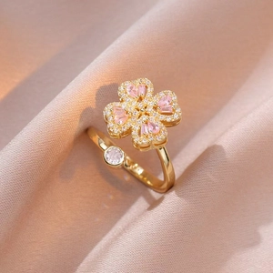 Macro di anello a quadrifoglio dorato con pietre rosa su tessuto di seta rosa