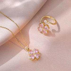 Conjunto de joyas de trébol de cristal rosa con collar y anillo sobre seda rosa