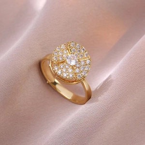 Drehbarer Goldring mit funkelndem Zirkonia auf champagnerfarbenem Seidenhintergrund