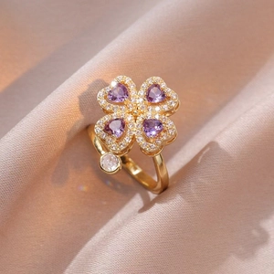 Dettaglio anello quadrifoglio dorato con pietre viola a cuore e zirconi bianchi brillanti