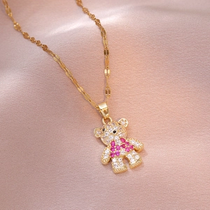 Golden bear pendant necklace with sparkling pink and white crystals on pink silk backdrop