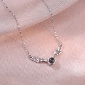 Elegant deer antler necklace with a dark projection stone on soft pink silk background
