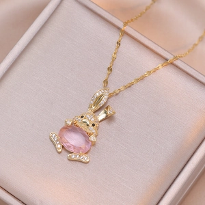 Collier lapin doré avec cristal rose et strass brillants sur un fond de satin satiné