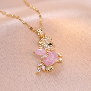 Golden rabbit pendant necklace with pink zircon crystals on soft silk background