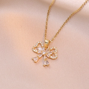 Elegant gold bow necklace with cubic zirconia pendant on luxury silk background