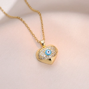 Collier cœur doré avec pendentif œil bleu et zircons étincelants sur fond en soie